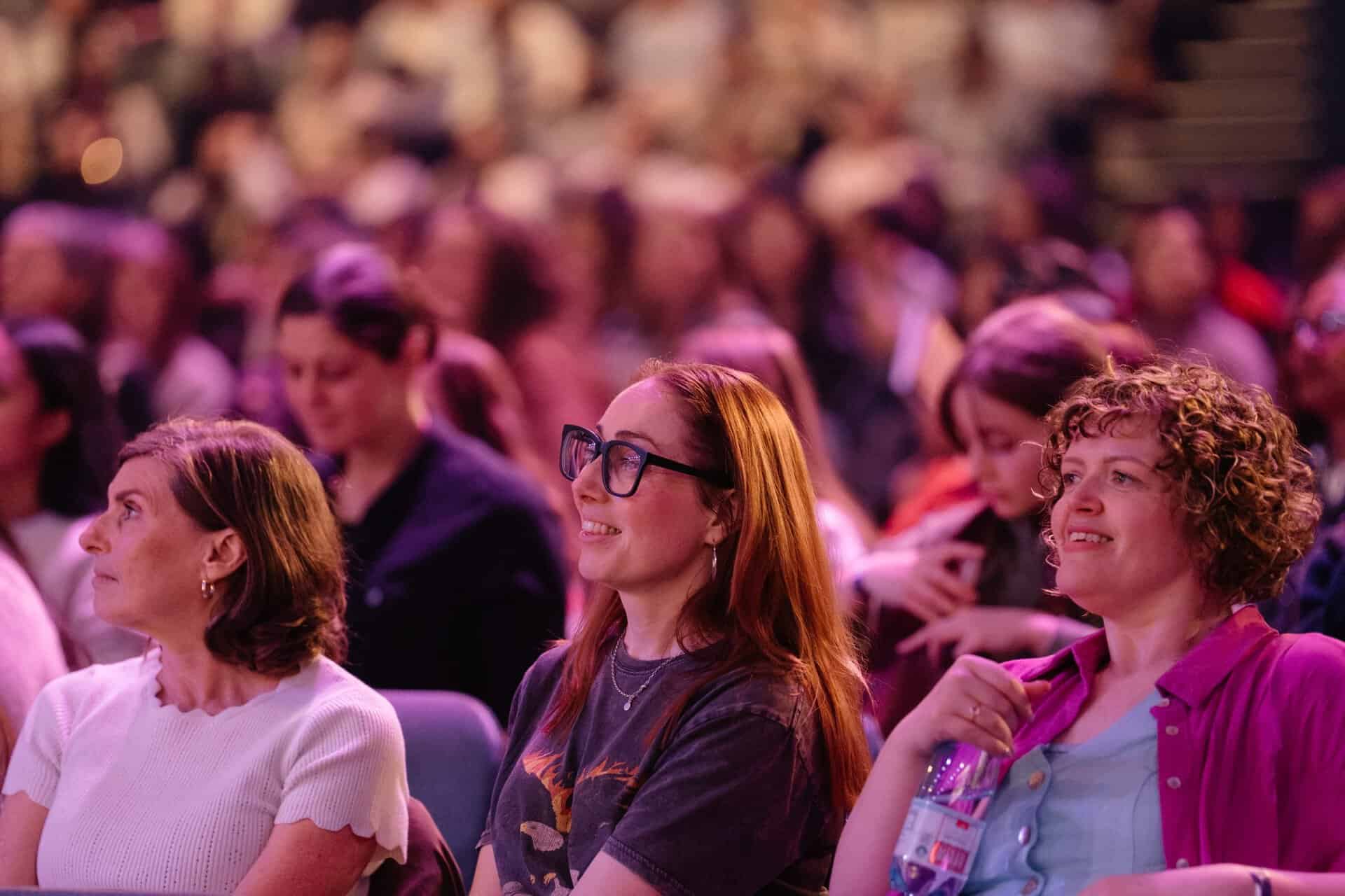 Diverse women attending the OneLove Women 2025 event in a large conference hall.