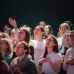 Women at OneLove Women 2025 event raising hands and engaging.